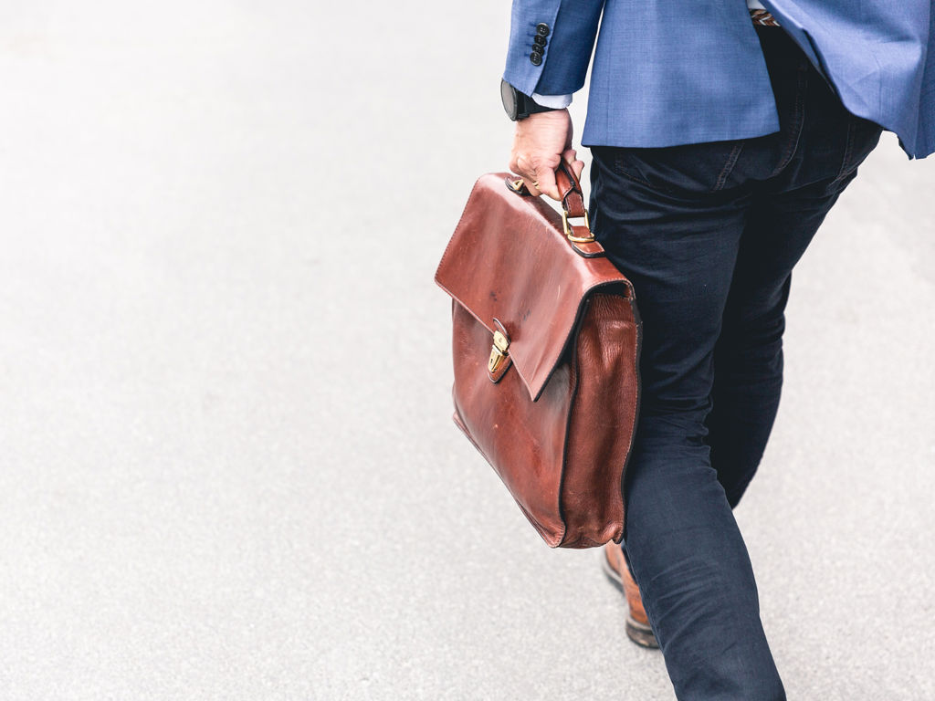 mand går med sin brune kuffert