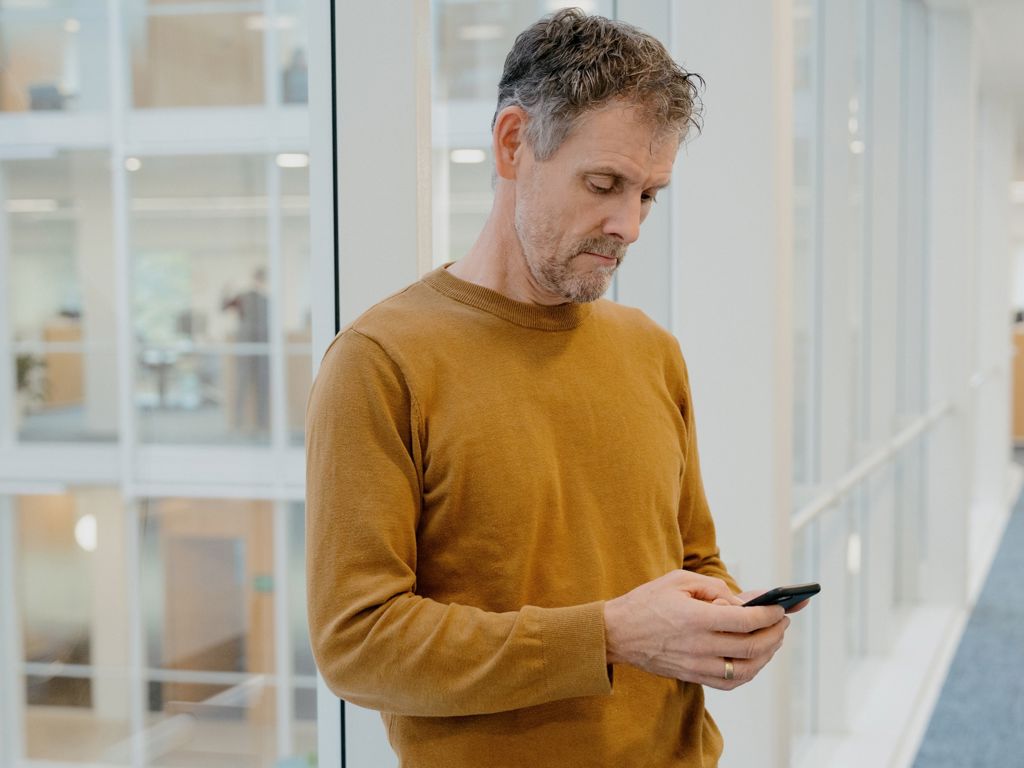 mand kigger ned i sin telefon