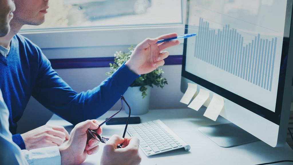 mand peger på sin computer med sin kuglepen