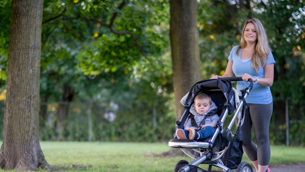kvinde går i en park med sin søn i klapvogn