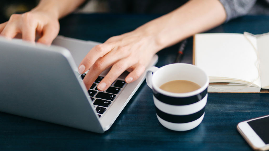 Skrivebord med computer og kaffekop