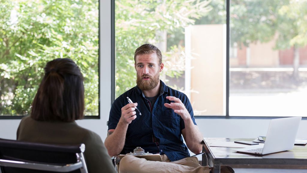 mand forklarer noget til en kvinde i et mødelokale