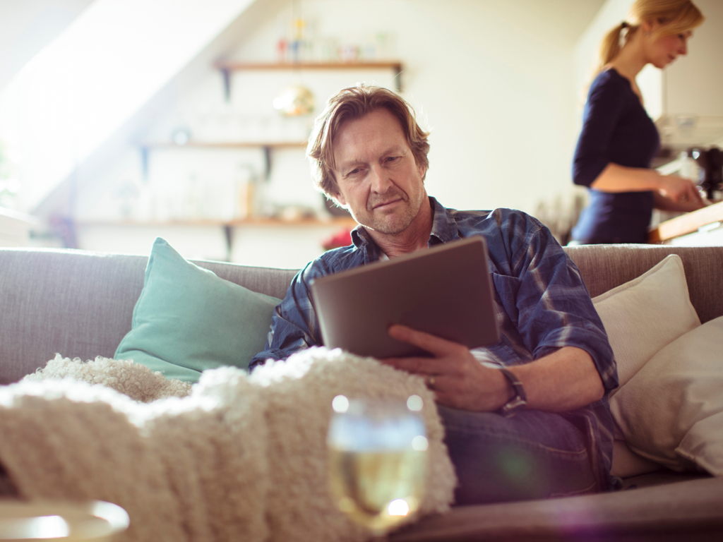En mand kigger på sin Ipad fra sin sofa