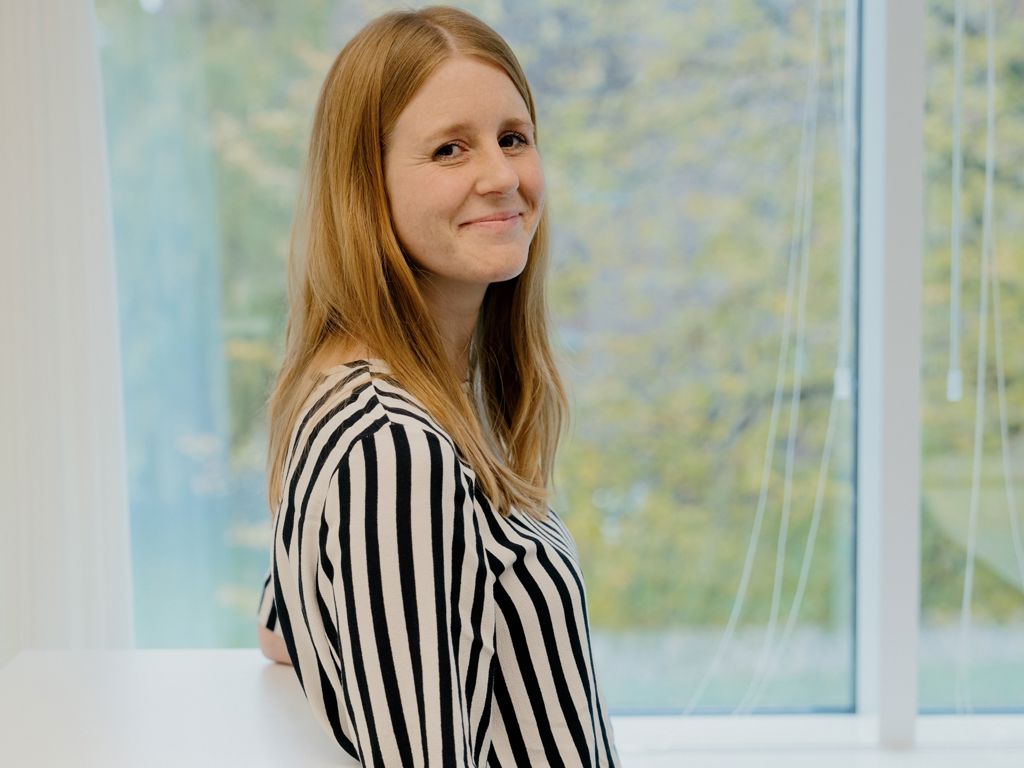 ung kvinde smiler foran et vindue