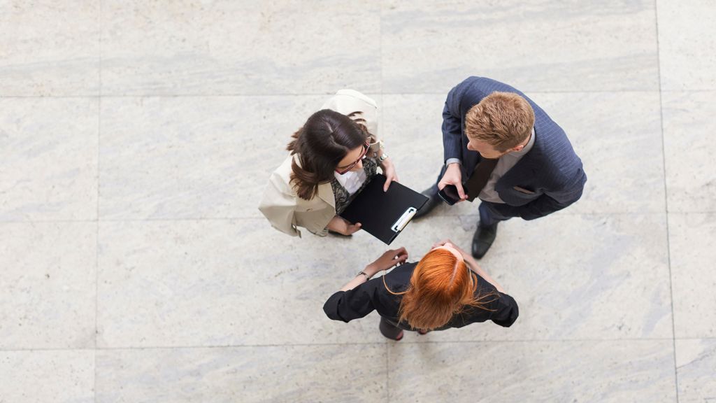 tre mennesker set oppefra står og snakker