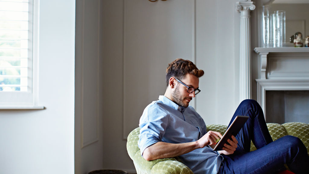 Mand i sofa der arbejder på Ipad