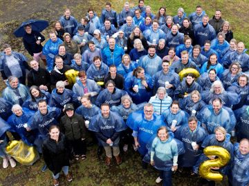 Fællesbillede af tillidsvalgte på græsplæne i regnvejr og regnslag