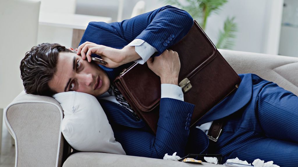 mand der taler i telefon i sofa samtidigt med, at han er syg