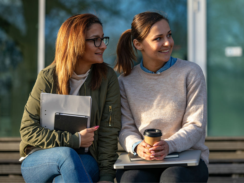 to unge kvinder sidder på en bænk